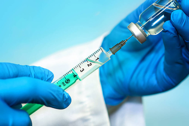 青い背景に注射器を備えた瓶の中のワクチン。医学、医療、科学の概念 - 写真・画像