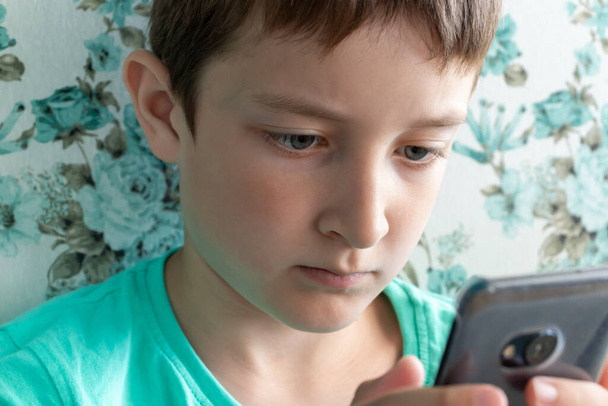 A teenage boy with serious face playing online games using smartphone. - Fotó, kép