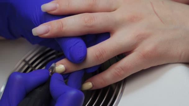 女性マニキュアマスターは、クライアントの爪から古いゲルを削除します。閉めろ。マニキュアサロンで電動ネイルドリル。美容室でのハードウェアマニキュア。サクショングリル. - 映像、動画