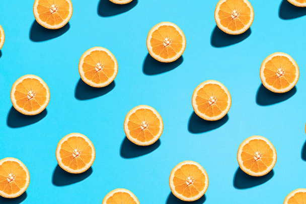 Orange pattern on bright light blue background. Minimal flat lay food texture. Summer abstract trendy fresh concept. - Photo, image