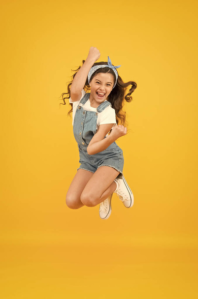Active girl feel freedom. Fun and relax. feeling free. carefree kid on summer holiday. time for fun. retro beauty in mid air. Jump of happiness. small girl jump yellow background. full of energy. - 写真・画像