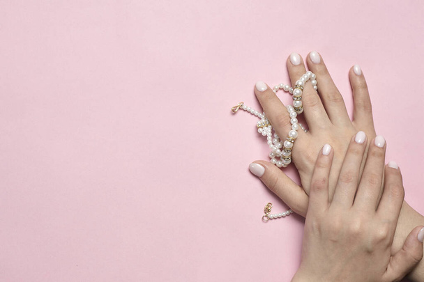 Hermosas manos femeninas con manicura sosteniendo perlas. Mujer mostrando las manos con elegante manicura femenina de moda. Cuidado de la piel
 - Foto, imagen