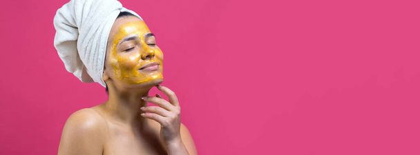 Beauty portrait of woman in white towel on head with gold nourishing mask on face. Skincare cleansing eco organic cosmetic spa relax concept. - Foto, Bild
