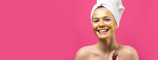Beauty portrait of woman in white towel on head with gold nourishing mask on face. Skincare cleansing eco organic cosmetic spa relax concept. - 写真・画像