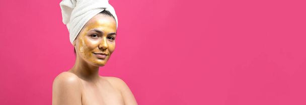 Bellezza ritratto di donna in asciugamano bianco sulla testa con maschera nutriente oro sul viso. Detergente per la pelle eco biologico cosmetico spa relax concept. - Foto, immagini