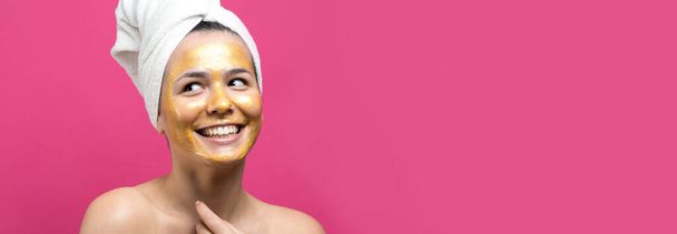 Beauty portrait of woman in white towel on head with gold nourishing mask on face. Skincare cleansing eco organic cosmetic spa relax concept. - 写真・画像