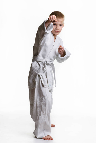 Karatepoika lyö oikealla kädellään, valkoisella taustalla
 - Valokuva, kuva