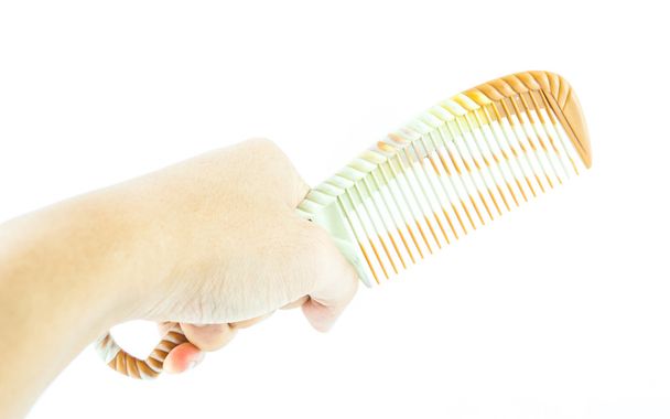 Коричневый гребень в руке изолированы на белом
 - Фото, изображение