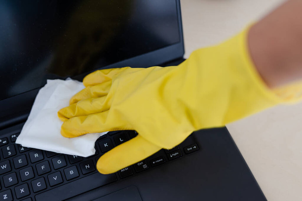 practice good hygiene against viruses and bacteria, hand with cleaning gloves disinfecting laptop keyboard with wipe - Photo, image