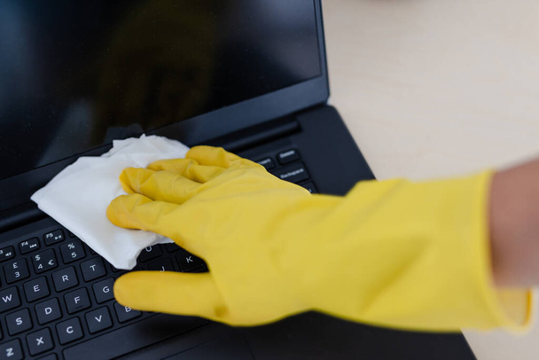 practice good hygiene against viruses and bacteria, hand with cleaning gloves disinfecting laptop keyboard with wipe - Photo, Image