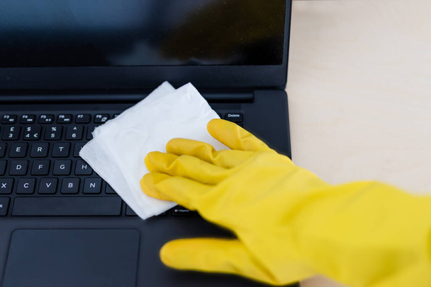 practice good hygiene against viruses and bacteria, hand with cleaning gloves disinfecting laptop keyboard with wipe - Foto, immagini
