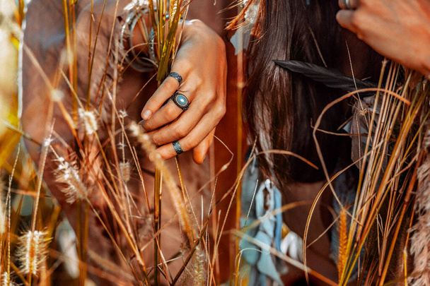 close up of woman hands wearing ethnical accessories on the field at sunset - Foto, immagini