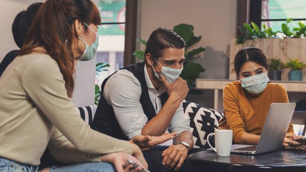 diverse business people caucasian and asian working together in business lobby of coworking space and everyone wearing medical mask to protect from coronavirus covid 19 infection, working in coronavirus outbreak situation - Фото, изображение