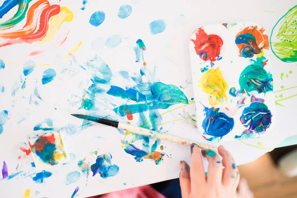 Ένα παιδί ζωγραφίζει με δάχτυλα, πινέλα και λαδομπογιές. - Φωτογραφία, εικόνα