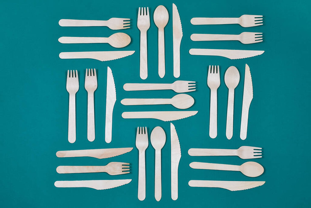Wooden spoons, forks, knives on a green background. Pattern. Zero waste concept. - Photo, Image