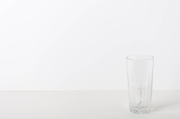 Tazza di vetro sul tavolo bianco su sfondo bianco. Composizione minima. Copia spazio
 - Foto, immagini