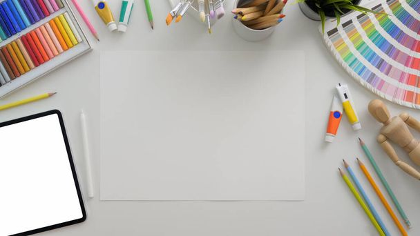Κάτοψη του χώρου εργασίας σχεδιαστών με mock-up tablet, sketch paper και προμήθειες σχεδιαστών σε λευκό γραφείο   - Φωτογραφία, εικόνα