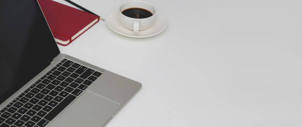 Обрізаний знімок мінімального робочого простору з ноутбуком, канцелярським приладдям, чашкою кави та місцем для тексту на білому столі
   - Фото, зображення