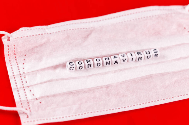 Koronavirové slovo z písmen na červeném pozadí. Nápis na koronaviru ochranné masky. - Fotografie, Obrázek