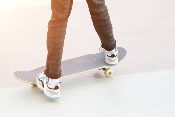 skateboard and legs of man riding on it close up outdoors - Zdjęcie, obraz