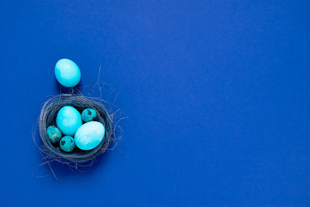 Feliz concepto de Pascua. La composición festiva primaveral azul los huevos menudos grandes en el nido sobre el fondo a la moda minimalista
. - Foto, Imagen