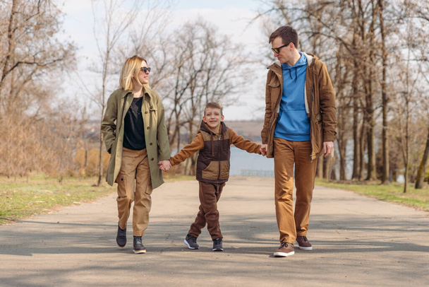 Młoda szczęśliwa rodzina ojciec matka i syn. spacer po parku miejskim - Zdjęcie, obraz