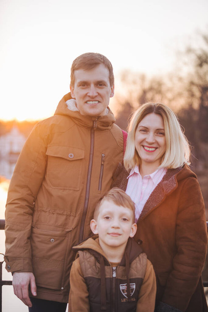 famiglia di tre ritratti in abito autunnale al tramonto. piccolo figlio madre e padre
 - Foto, immagini