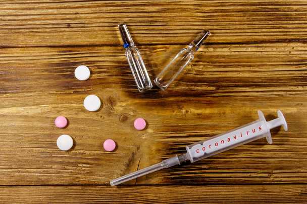 Concept of a prevention and treatment coronavirus. Pills, syringe, ampoules on a wooden background. Novel coronavirus outbreak. Epidemic from Wuhan, China - Photo, Image