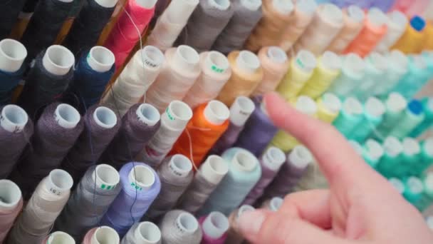 Wideo kobiety wybierającej kolorowe szpuli nici - Materiał filmowy, wideo