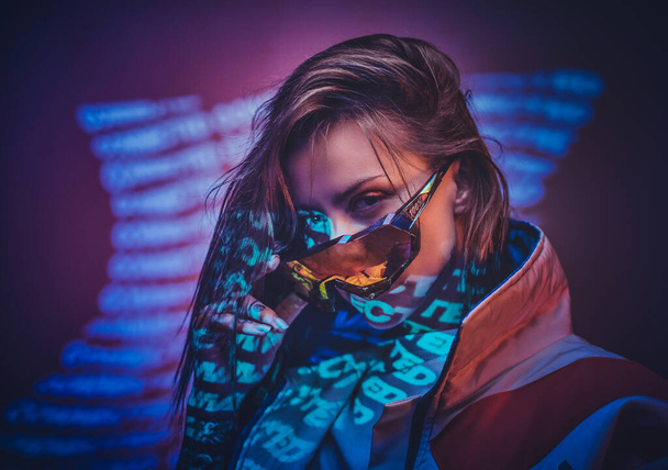 Eingefärbte attraktive Frau posiert in einem Neonlicht eines Ateliers mit Text, sieht selbstbewusst aus - Foto, Bild