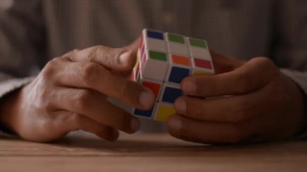 Cierra las manos del hombre de negocios resolviendo el rompecabezas del cubo de Rubik en el escritorio. Solución de problemas en el trabajo concepto
. - Imágenes, Vídeo