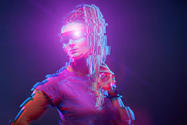 Young girl in sunglasses looking at camera in neon light. Image with glitch effect. - Foto, Imagem