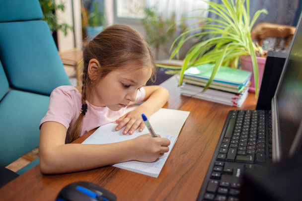 Holka ze školy dělá domácí úkoly před počítačem. Vzdálenost nebo domácí výuka - Fotografie, Obrázek