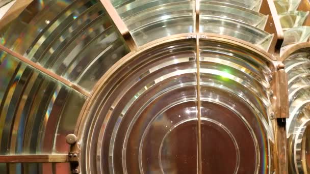 Fresnel lens met messing structuur, nautische vuurtoren. Detail van de glazen lantaarn met regenboog spectrum. Systeem van lampen en lenzen om te dienen als navigatiehulpmiddel. Oude zee zoeklicht baken. - Video