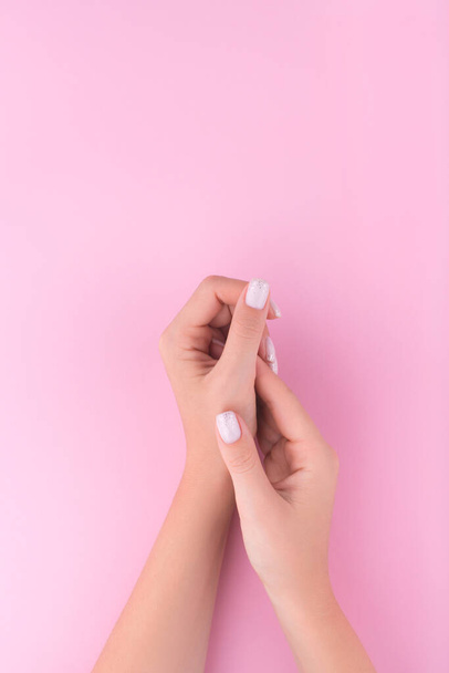 Beautiful young woman's hand with manicure on pink background. Flat lay style. Top view. Place for design.  - Photo, Image