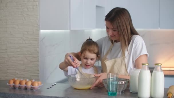 glückliche Familie in der Küche Mutter und Tochter in der Küche spielen mit Mehl, um Spaß zu haben und die Pasteten in der Küche in den gleichen roten Schürzen formen. Stedicam. - Filmmaterial, Video