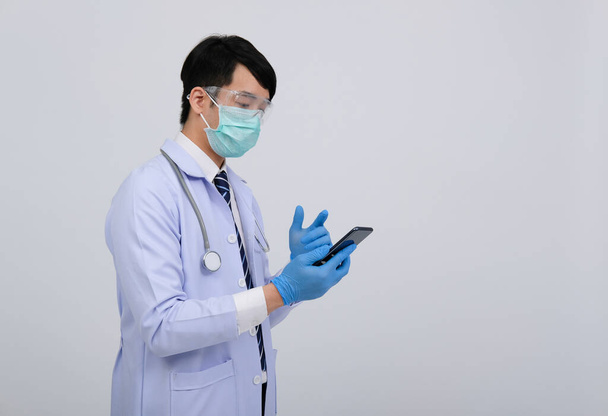 médico médico practicante con máscara con teléfono inteligente y estetoscopio sobre fondo blanco. medicina profesional medicina concepto de salud
 - Foto, imagen