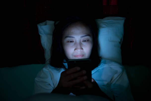 Asian woman playing game on smartphone in the bed at night,Thailand people,Addict social media - Photo, image