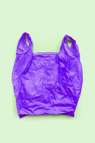 Purple plastic bag on green background. Environment pollution concept. Top view - Foto, Imagem