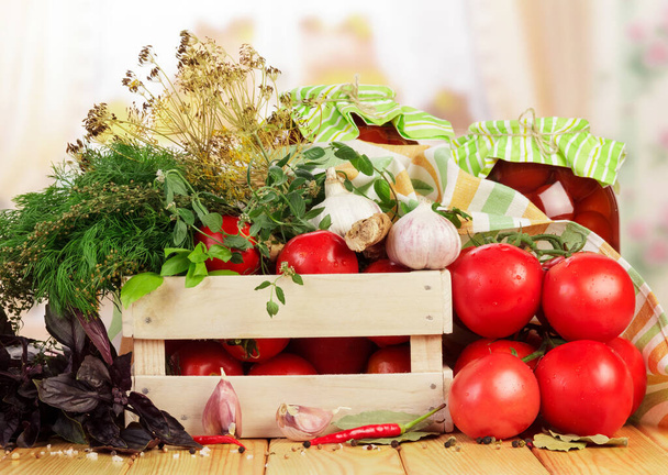Drewniane pudełko świeżych pomidorów i słoiki marynowanych przypraw izolowane na białym tle. - Zdjęcie, obraz