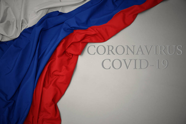schwenken bunte russische Nationalflagge auf grauem Hintergrund mit Text Coronavirus covid-19. Konzept. - Foto, Bild