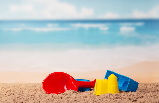 Children's toys castles and shovel in the sand against the sea. - Foto, afbeelding