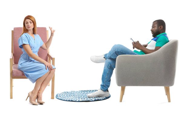 Προσβλημένη σύζυγος μετά από καυγά με τον σύζυγό της που κάθεται στην πολυθρόνα σε λευκό φόντο - Φωτογραφία, εικόνα