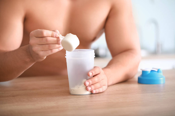 Sporty man making protein shake at home, closeup - Foto, afbeelding