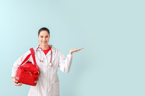 Renk arkaplanında bir şey gösteren çantalı kadın sağlık görevlisi - Fotoğraf, Görsel