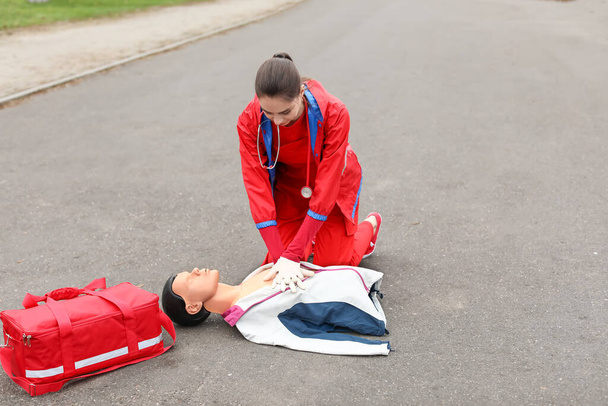Paramedic demonstrating CPR on mannequin outdoors - Photo, Image
