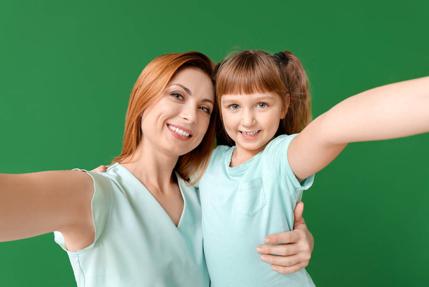 Woman and her little daughter taking selfie on color background - Photo, Image
