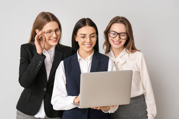 Beautiful young businesswomen with laptop on light background - Photo, Image