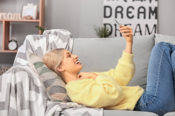 Fiatal nő mobiltelefon csinál selfie otthon - Fotó, kép
