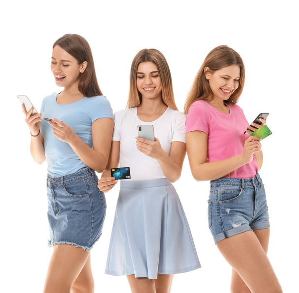 Jonge vrouwen met mobiele telefoons en creditcards op witte achtergrond. Online winkelen concept - Foto, afbeelding